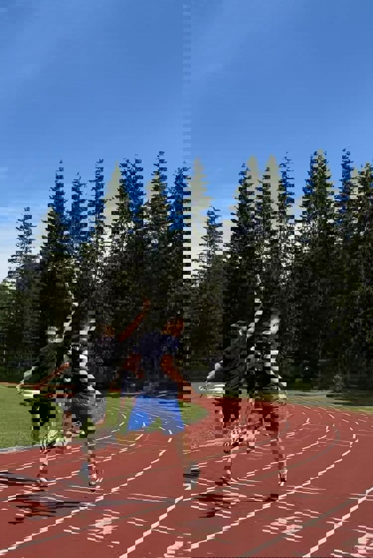 En gruppe mennesker som løper på en bane med trær i bakgrunnen