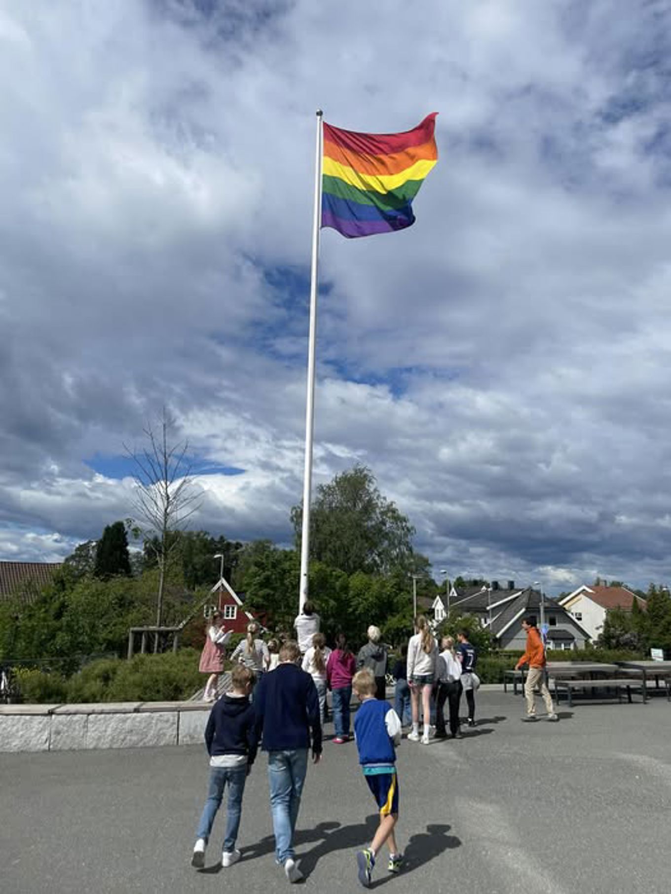 en gruppe mennesker som går på en gate med et flagg vaiende i luften