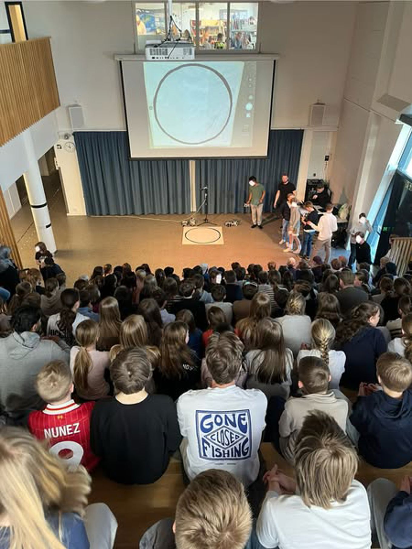 en gruppe mennesker som sitter i et rom og ser på en person på en scene en gruppe mennesker som sitter i et rom og ser på en person på en scene