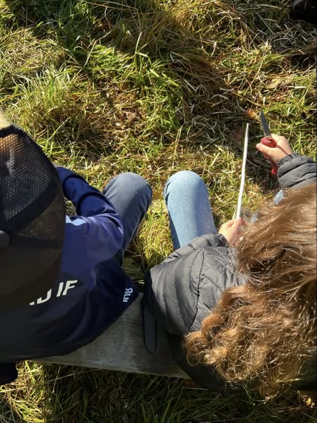 en person som ligger på bakken og holder en penn