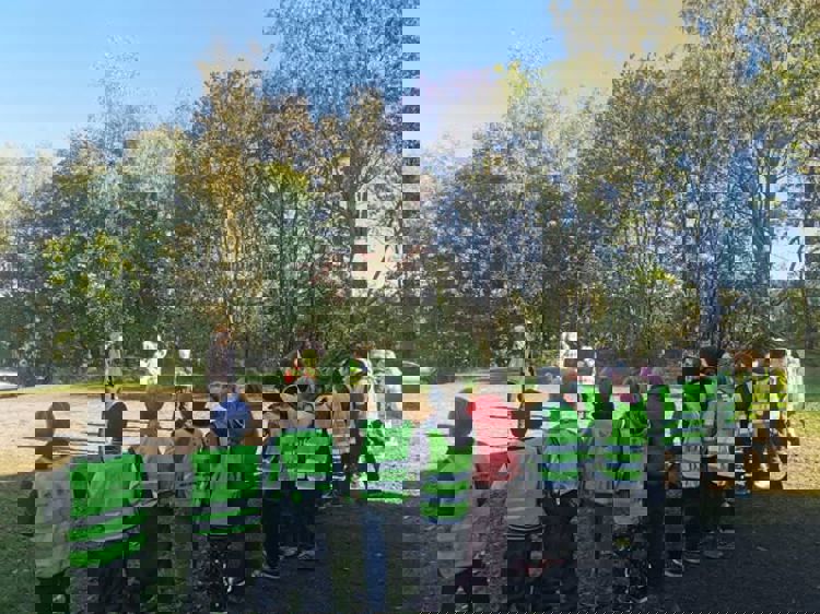 En gruppe mennesker i vester som står på et jorde