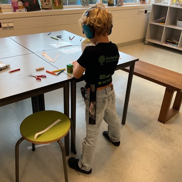 et barn som står foran et skrivebord med en stol og en bok