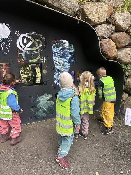 En gruppe barn som ser på et maleri på en vegg