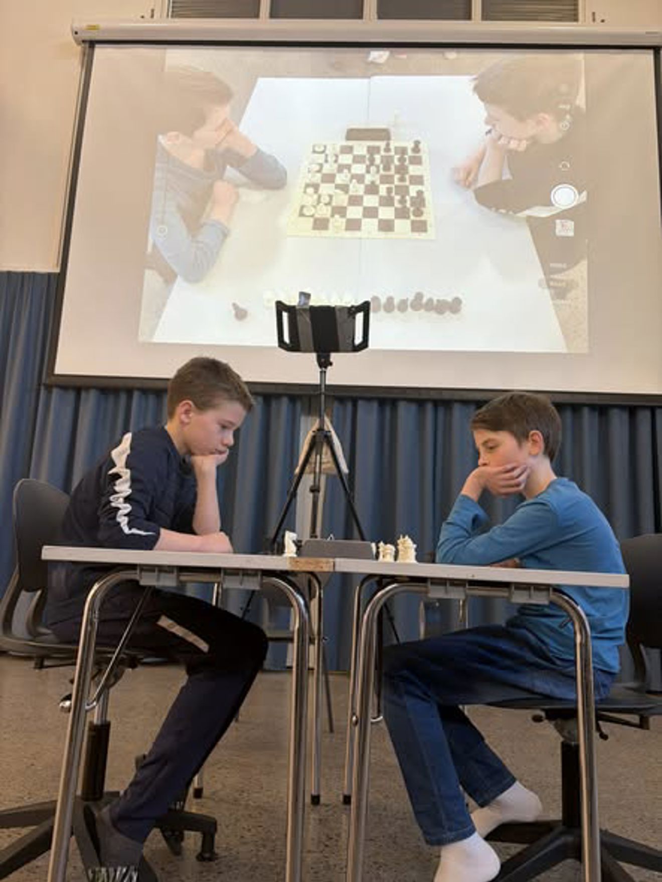 et par menn som sitter ved et bord med en projektorskjerm bak seg